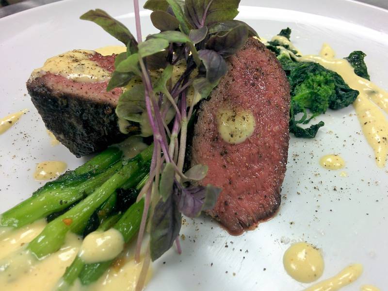 An artistically displayed plate of steak with a creamy sauce