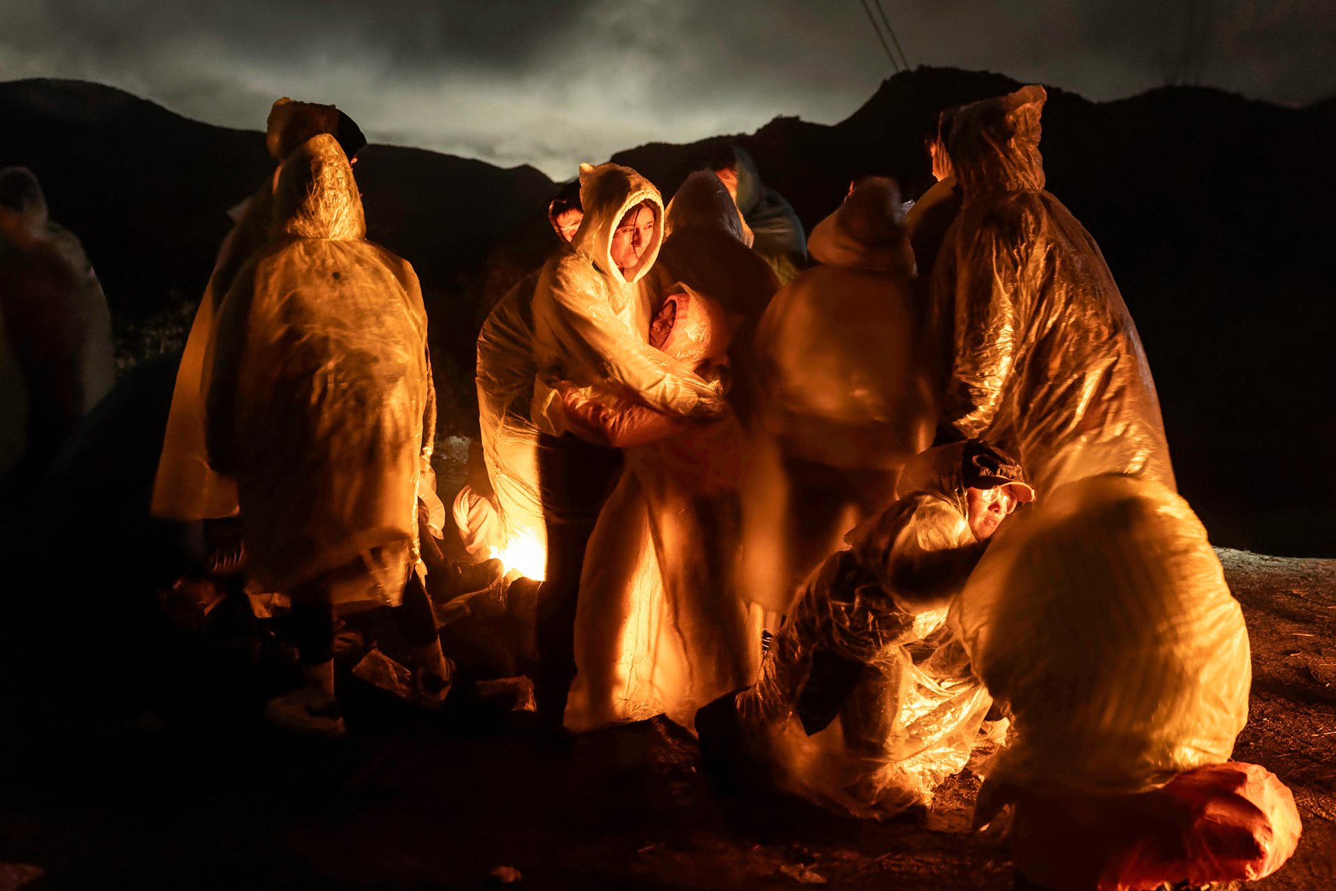 Chinese migrants warm themselves under a cold rain after crossing the US-Mexico border, in Campo, California.