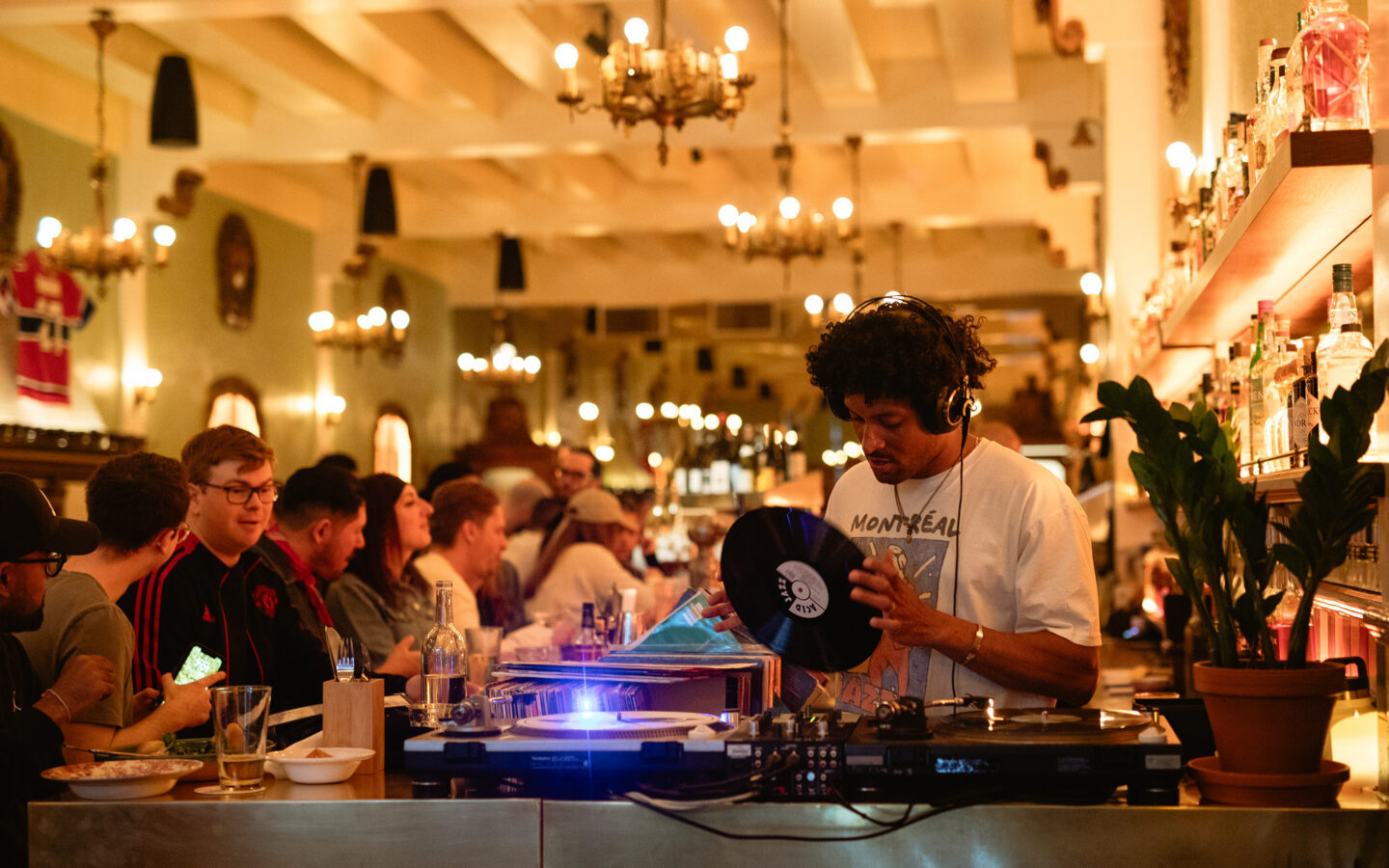 Vinyl DJ and guests inside Bar Dominion’s chandelier-lit room