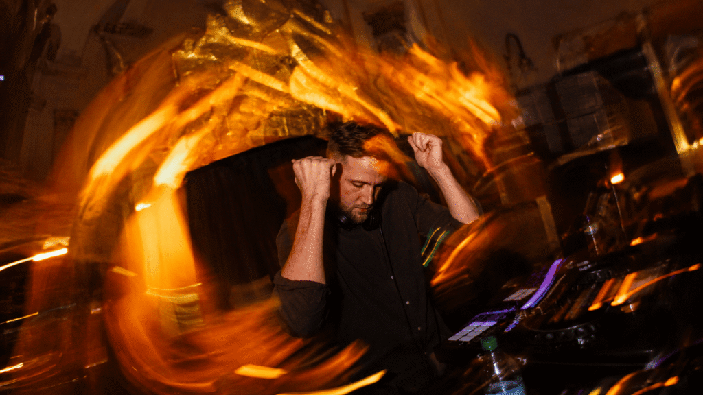 DJ performing amid dramatic orange light trails.